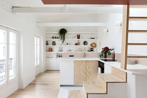 cocina abierta en l con armarios de madera natural y color blanco, frente rosa y grifo dorado