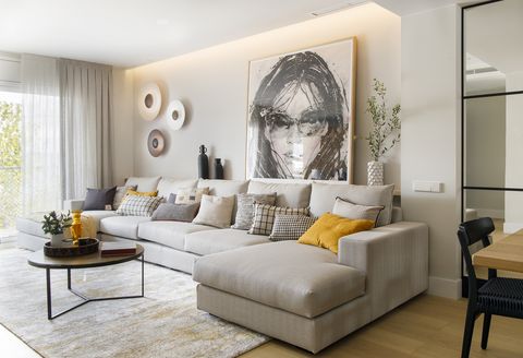 sofá con chaiselongue beige moderno y cuadro con la ilustración de una mujer
