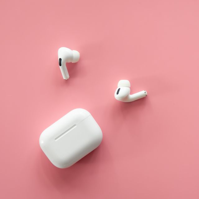 wireless in ear headphones with a case on a pink background, flat lay, conceptual minimalism