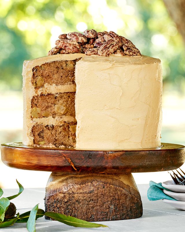 apple layer cake on a wooden cake stand outdoors with salted caramel frosting and candied pecans
