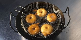 Apple rings coated in batter deep-frying in pan