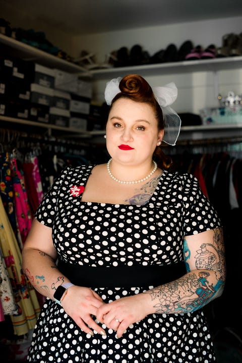 portrait of sex trafficking survivor, arien, wearing a black and white polka dotted dress, standing up in closet