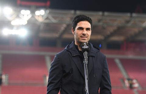Arsenal manager Mikel Arteta smiles as he speaks to the media as he stands in an empty football stadium in front of a branded UEFA Europa League microphone