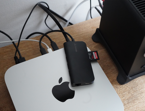 gümüş renkli bir mac mini ve üzerinde siyah kordonlar olan kahverengi bir masa