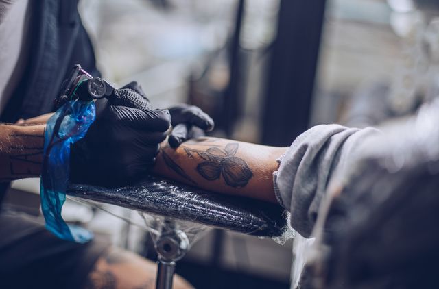 artist drawing tattoo on a hand