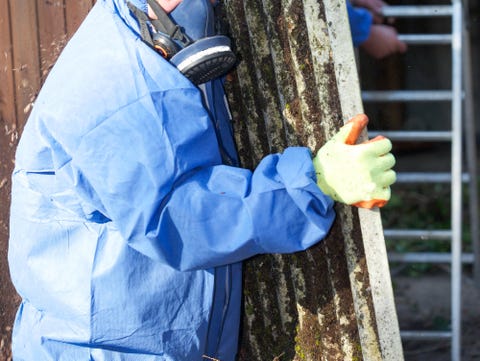 Asbestos corrugated roofing sheet being removed and sealed