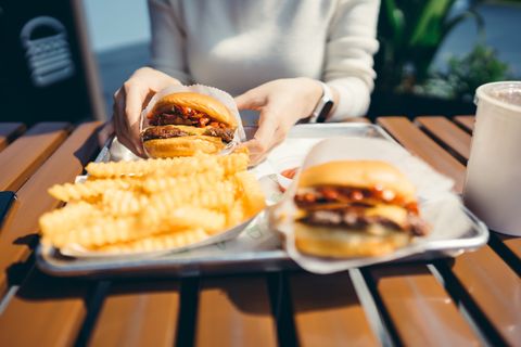 asian woman enjoying freshly made delicious burger with fries