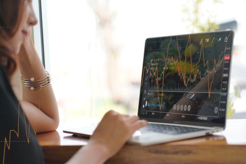 asian woman looking stock market graph at monitor screen 