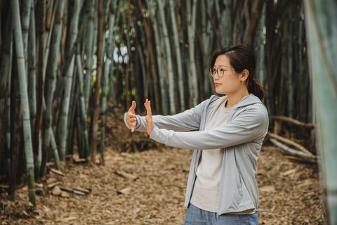 asian woman practicing tai chi in a bamboo forest