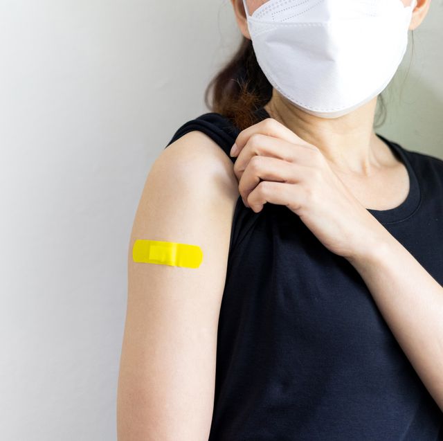 asian woman wear face mask using adhesive bandage yellow at arm after injection vaccinated on white isolate background covid 19 vaccine disease preparing