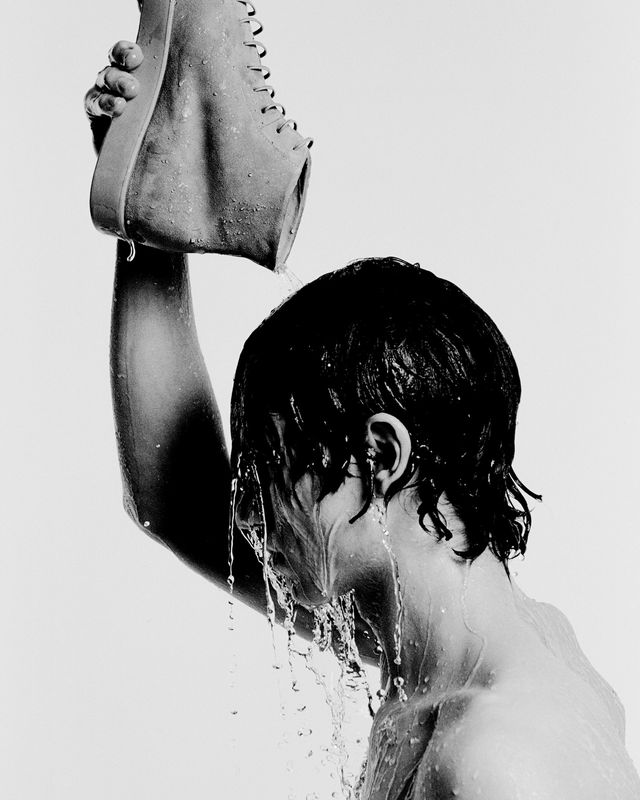uomo che si bagna la testa da una scarpa, foto in bianco e nero