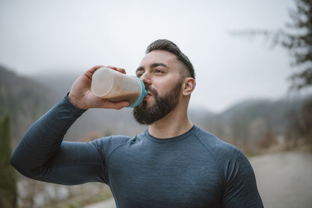 athlete drinking protein shake after outdoor workout