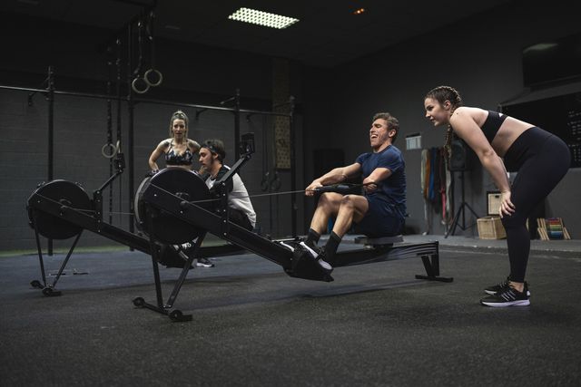 athletes exercising with rowing machine at gym
