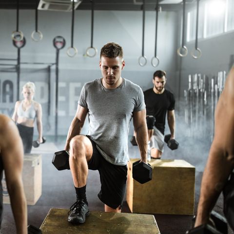 Athletic people having cross training with dumbbells in a gym.