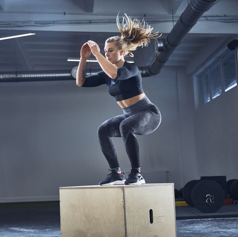 athletic woman doing box jump exercise at gym