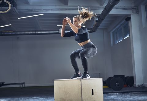 athletic woman doing box jump exercise at gym