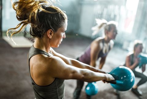 Athletic woman exercising with kettle bell on a class in a health club.