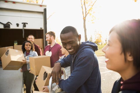 Smiling volunteers unloading cardboard boxes from truck