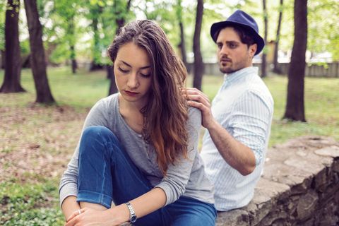 Attractive woman in the park looking troubled and unhappy and sitting away from her boyfriend