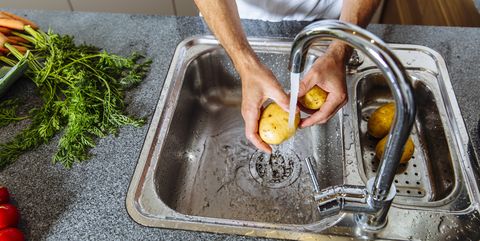 austria, man in kitchen washing vegetables