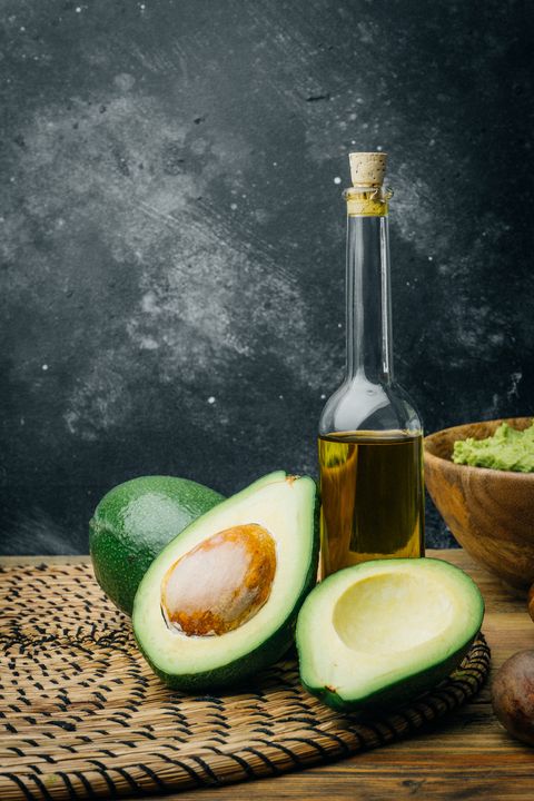 Avocado and avocado oil on a wooden background. Copy space.