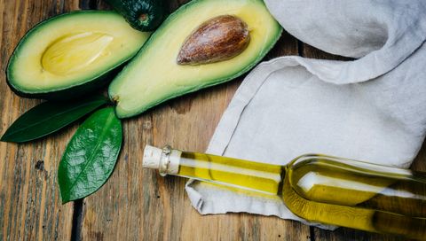 Avocado and avocado oil on a wooden background.
