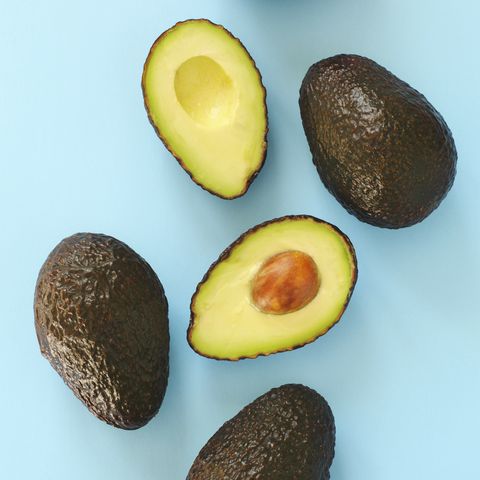 Avocado halves and whole on a blue speckle, top viev.