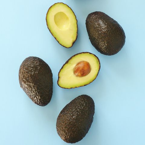 avocado halves and whole on a blue speckle top viev royalty free image 961634702