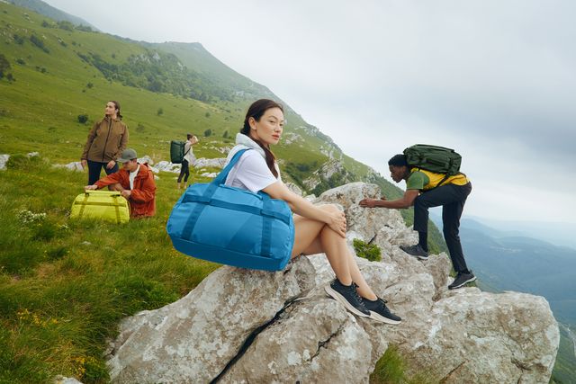 people in field and climbing on rocks with away luggage