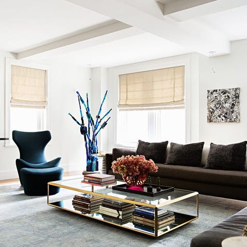 living room area with brown sofa and two tier glass coffee table and teal colored armless chairs