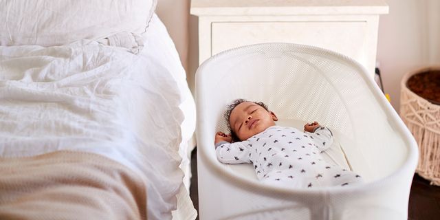 baby sleeping in bassinet next to bed