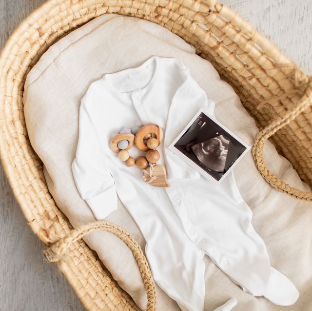 a baby footie, grasping toy, and ultrasonography in a woven basket