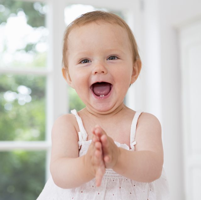una niña de un año, con dos dientecitos, sonríe