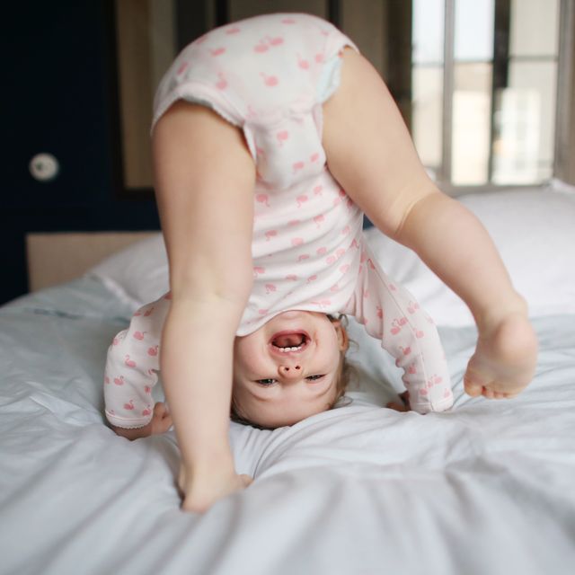 a baby girl playing on a bed