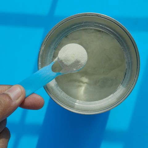baby milk powder on spoon on color background
