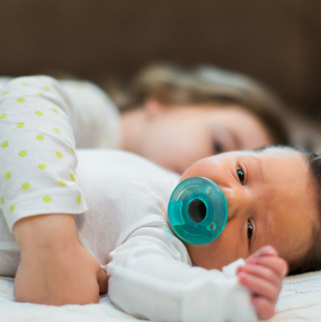 sister hugging infant with pacifier