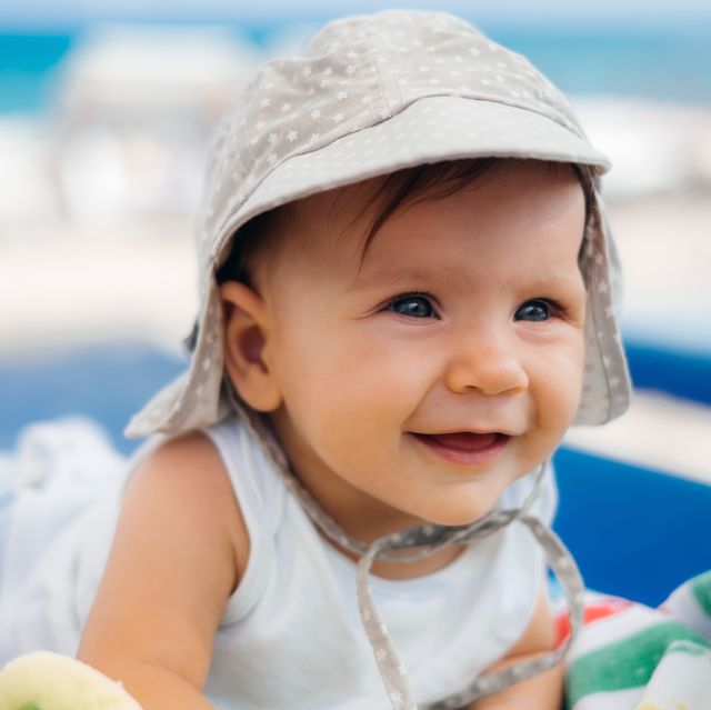baby wearing sun hat lounging on beach