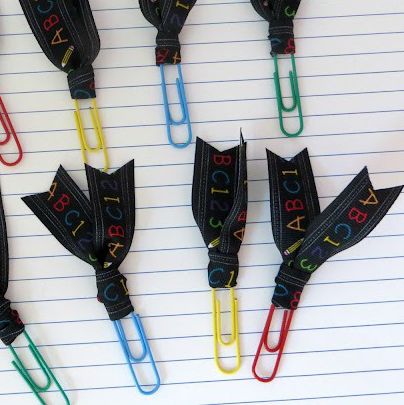 paper clips with ribbons tied on the m to act as bookmarks photographed against a sheet of lined paper the craft is a good housekeeping pick for best back to school activities