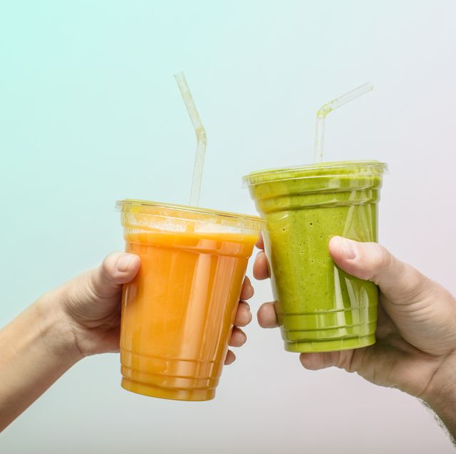 young man and womans hands toasting with fruit and vegetable smoothies in plastic cups