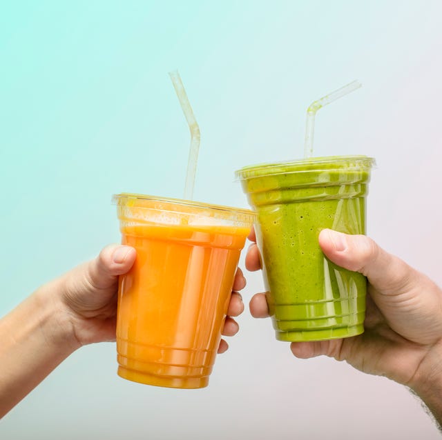 young man and womans hands toasting with fruit and vegetable smoothies in plastic cups