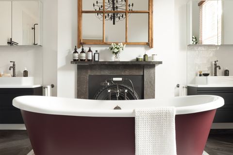 baño de estilo clásico con bañera exenta color vino y chimenea de piedra