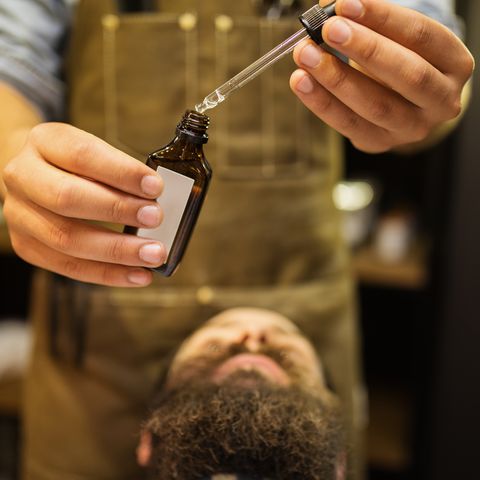 Barber putting beard oil to client