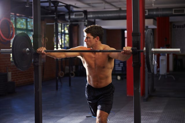 Bare Chested Man In Gym Preparing To Lift Weights bare chested man in gym preparing to lift weights