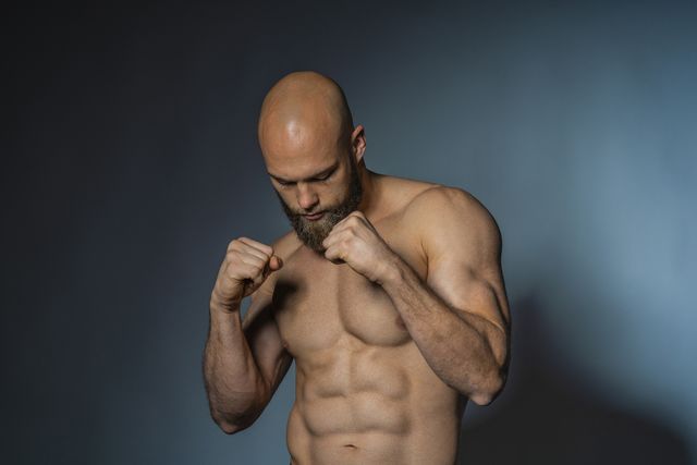 barechested athlete in boxing pose in studio