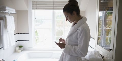 Vrouw in badkamer met telefoon temperatuur meten om vruchtbaarheid te checken