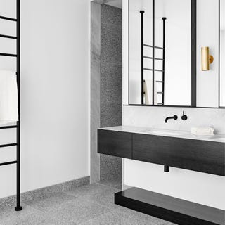 Bathroom clad in grey terrazzo tiles with black details