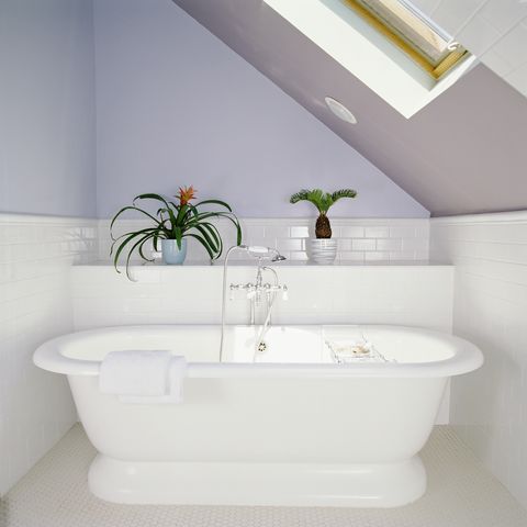 bathtub under skylight in attic bathroom with lilac purple walls