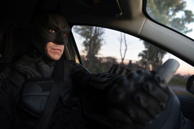 un hombre disfrazado de batman conduce un coche
