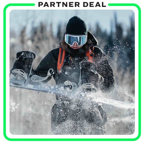 man in backcountry gear shaking off snow from snowboard