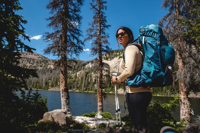 woman hiking in forest with backcountry gear
